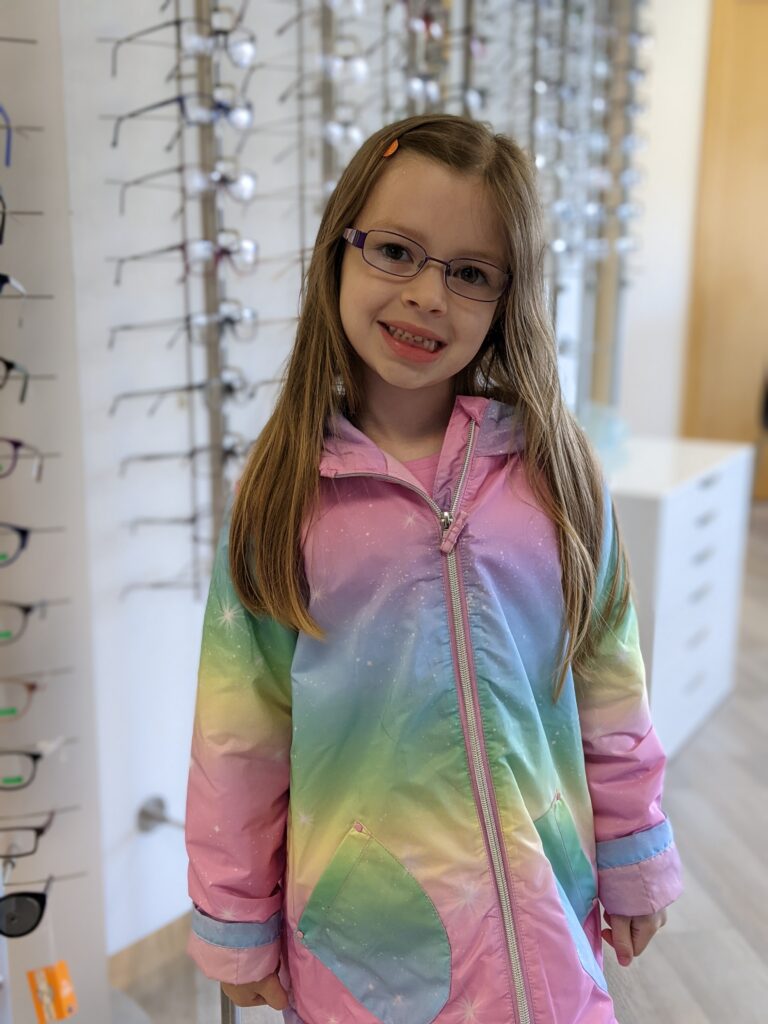 little girl at optometrists clinic wearing new pair of glasses